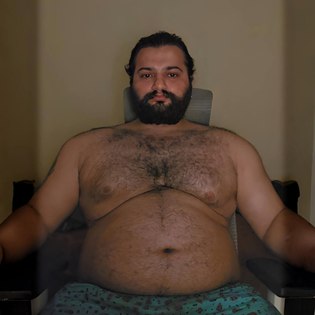 Shirtless image of me sitting on a chair during my relapse phase as a trader and fitness coach, showing noticeable weight gain.