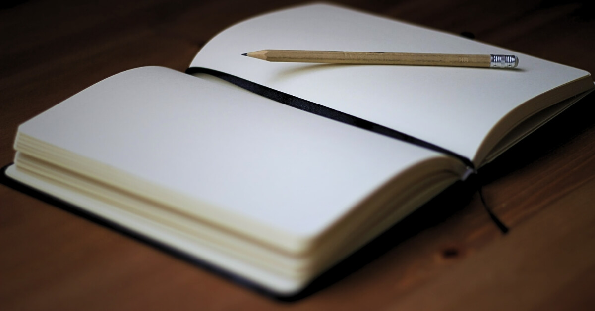 Open blank notebook with a wooden pencil on a wooden desk, symbolizing first-principles thinking and learning.