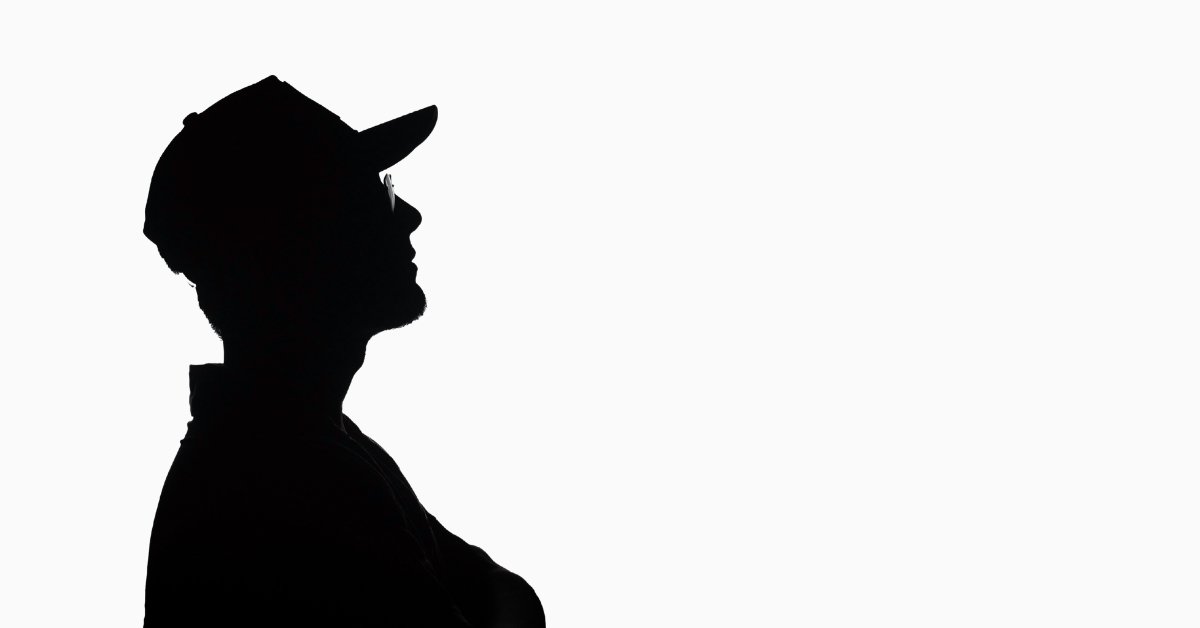 Silhouette of a person in a cap looking upward against a minimalist white background, representing leverage, long-term thinking, and personal growth through fitness and trading.